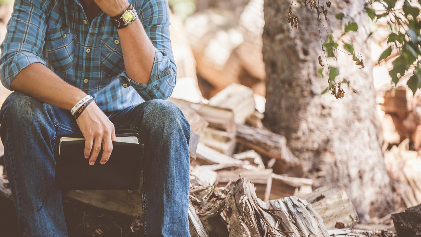 man pondering with a notebook in nature