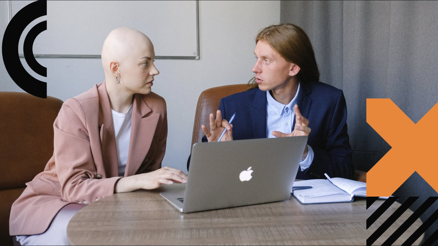 two coworkers having a conversation in front of a laptop