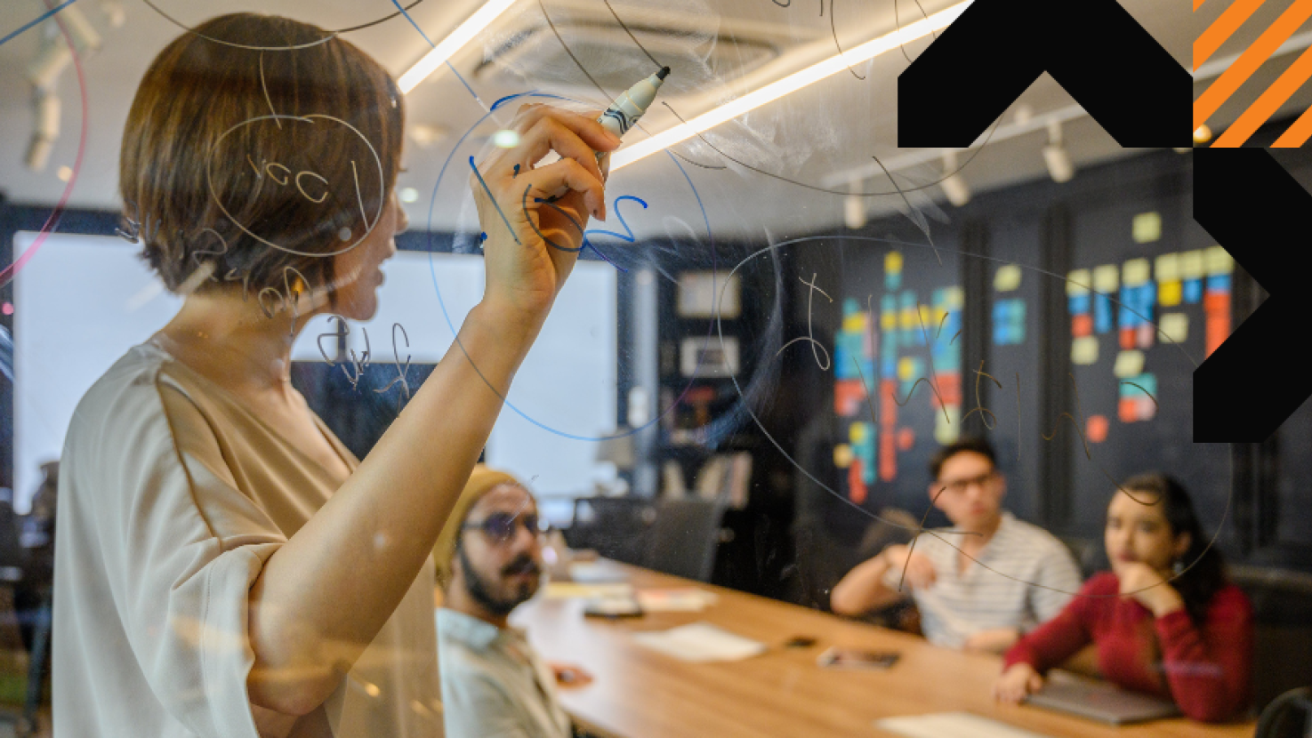 Team members writing on a white board & discussing in a boardroom